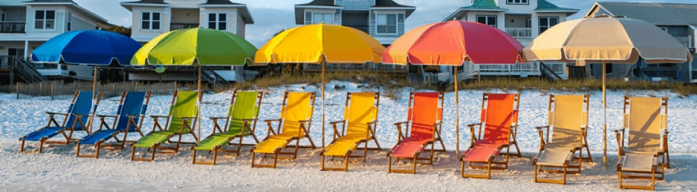 Color-coordinated beach umbrellas and matching lounge chairs arranged in a row on sandy shoreline, showcasing vibrant commercial outdoor branding for resorts and coastal properties
